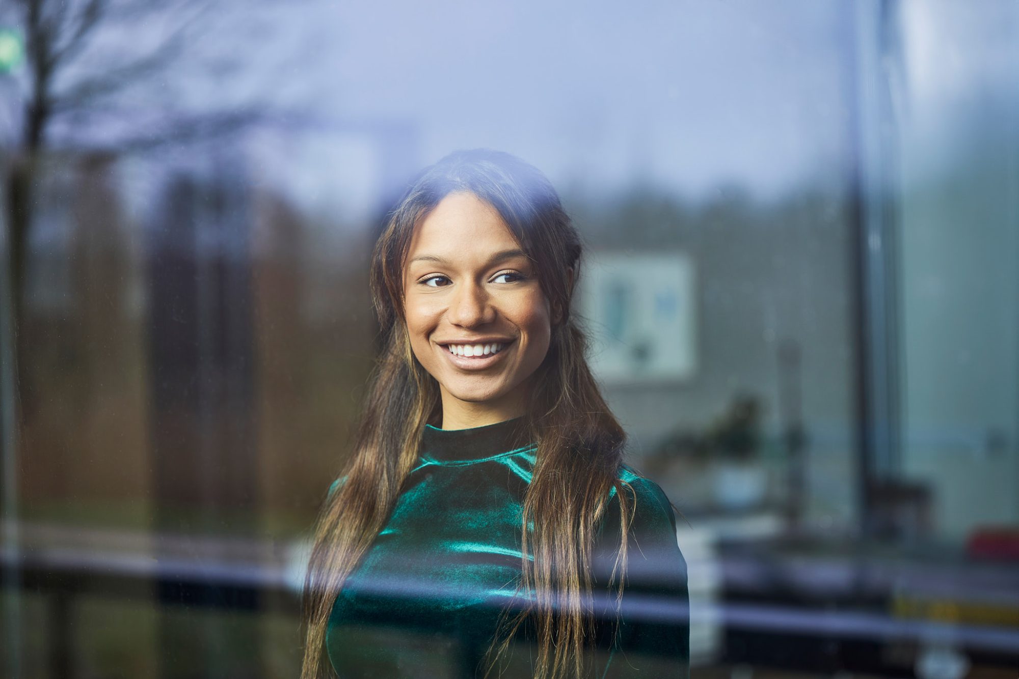Vrouw kijkt lachend en voldaan uit het raam